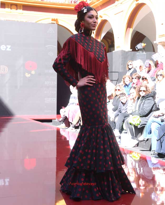 Traje de flamenca negro de lunares rojos a juego con capita, mañanita o mantoncillo rígido de Lucía Márquez en Huelva Flamenca