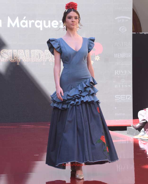 Traje de flamenca vaquero en dos tonos de azul con bordados de rosas rojas en el vuelo de Lucía Márquez en Huelva Flamenca